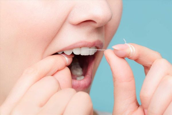 Sử dụng chỉ nha khoa để loại bỏ thức ăn thừa dính trên răng